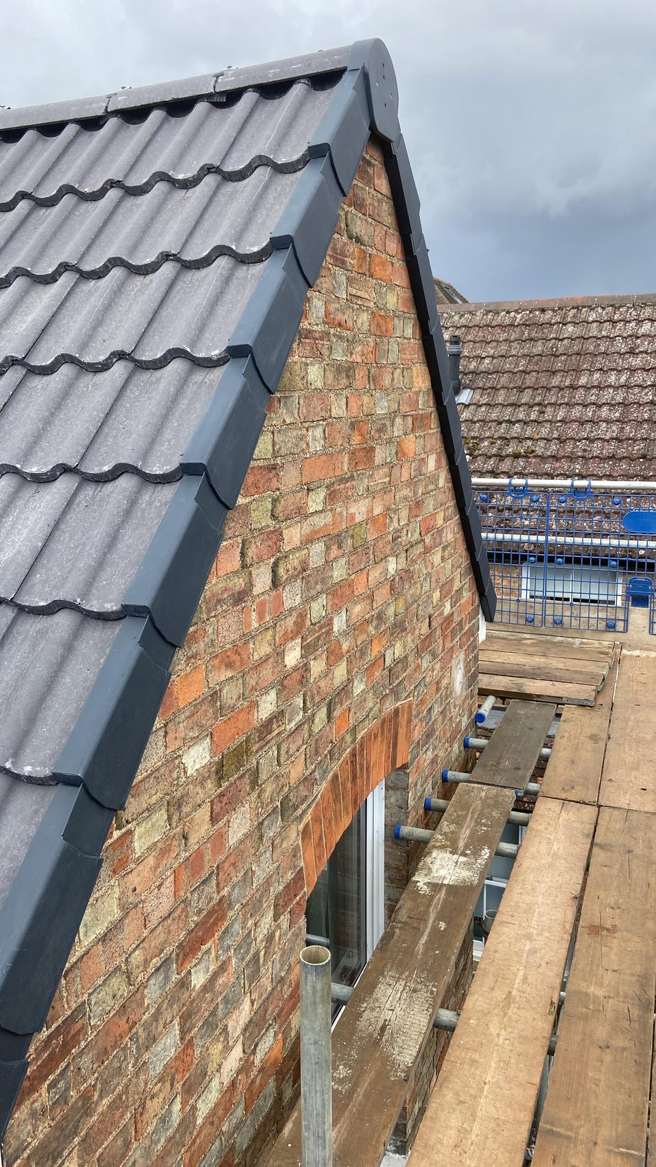 New anthracite dry verge fitted down a gable edge above the old brick wall