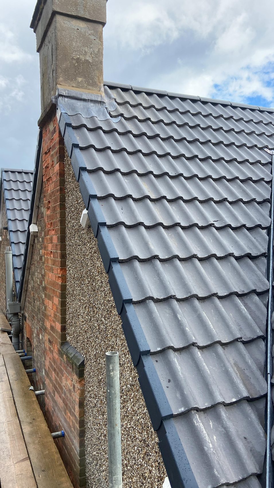 Anthracite dry verge run down the gable edge beside a chimney on the new roof