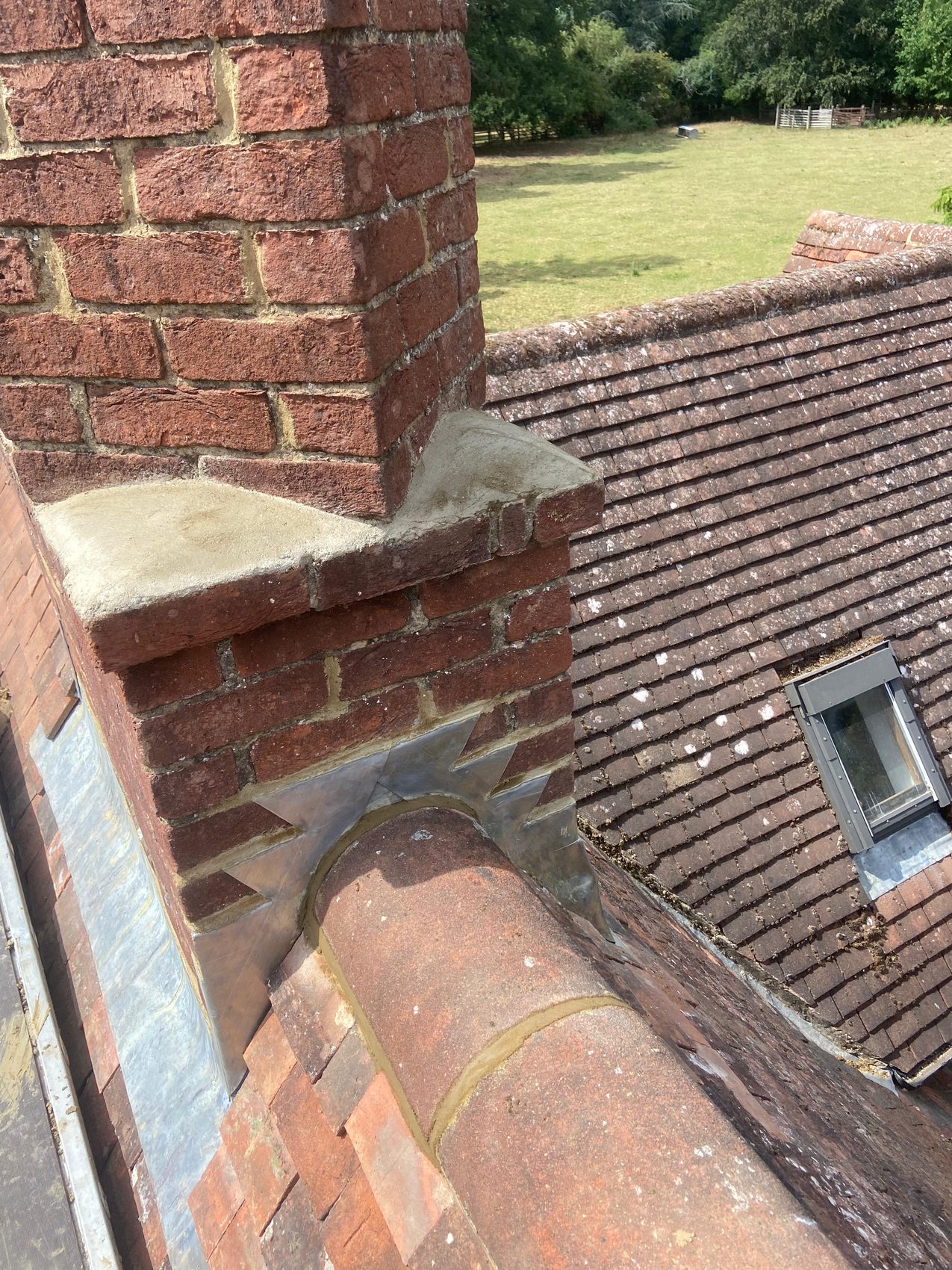 Chimney base with new lead flashing and re-bedded ridge tile meeting the tiled roof