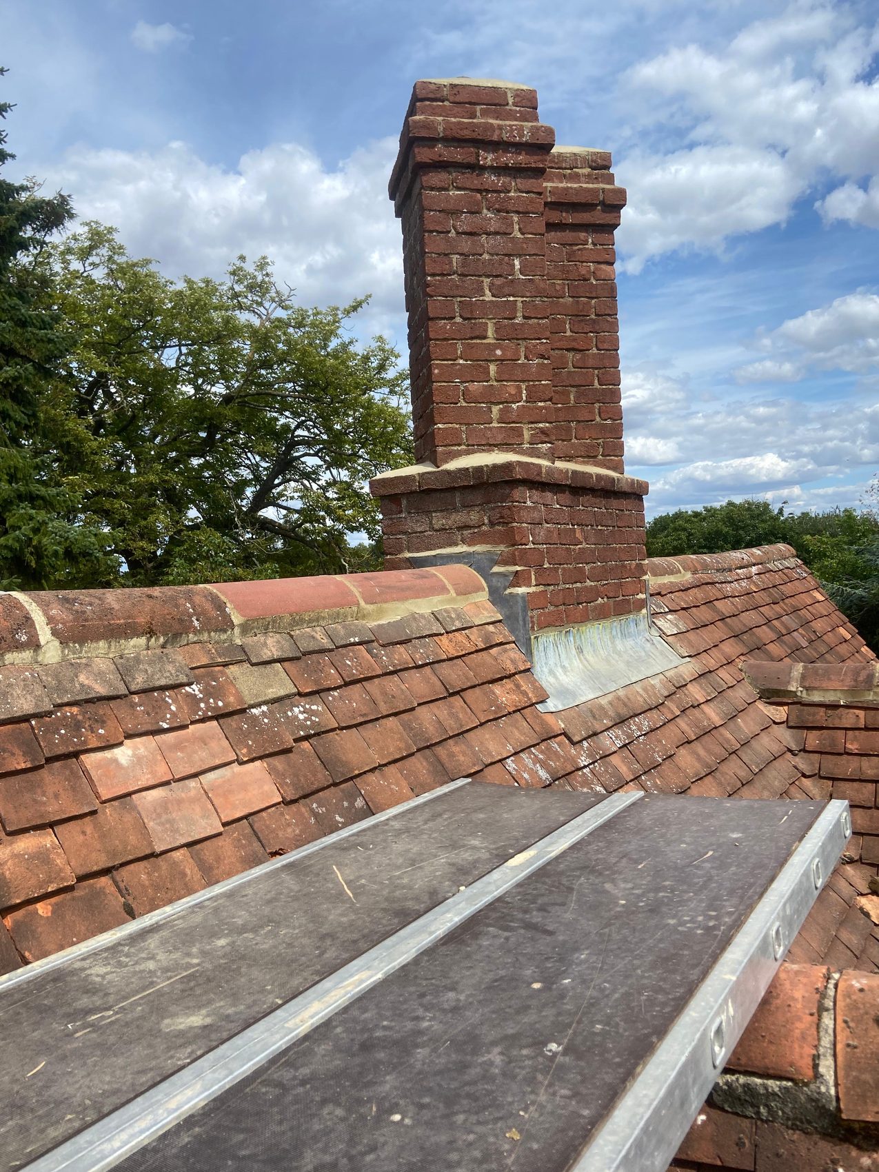 Completed chimney repair and ridge renewal against a clear sky