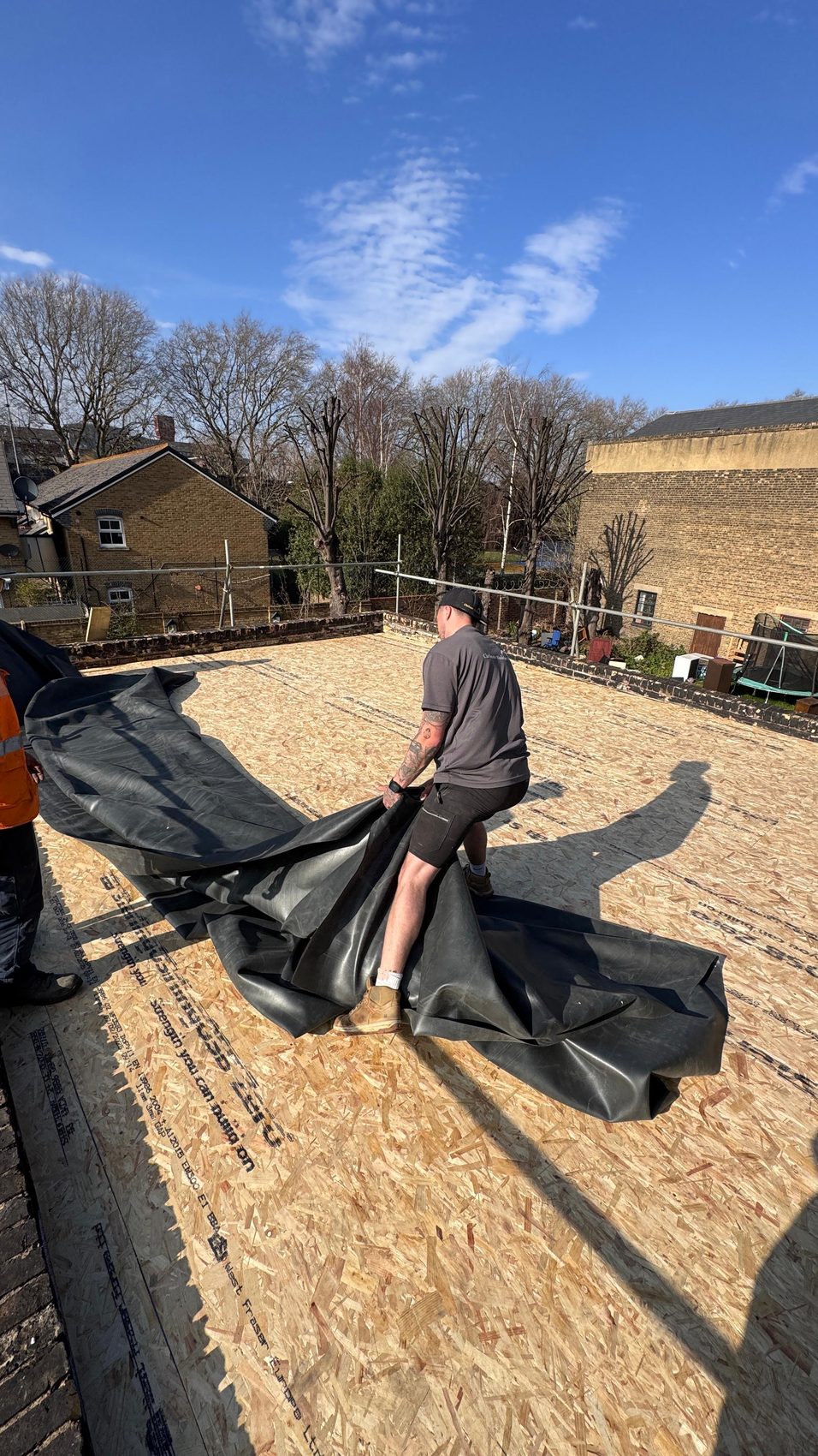 Black single-ply EPDM rubber membrane dressed out across the rebuilt flat-roof deck