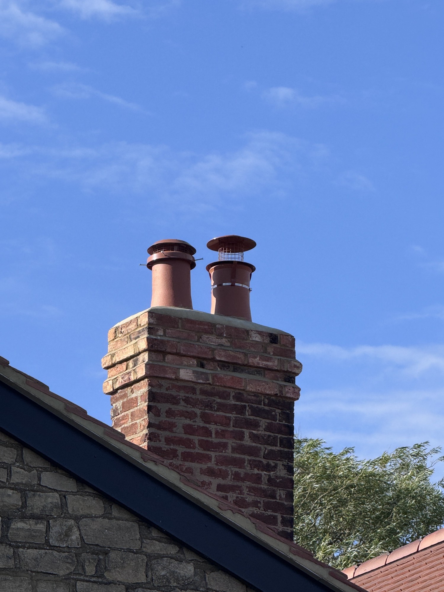 Rebuilt brick chimney with three terracotta pots on a new clay-tile roof