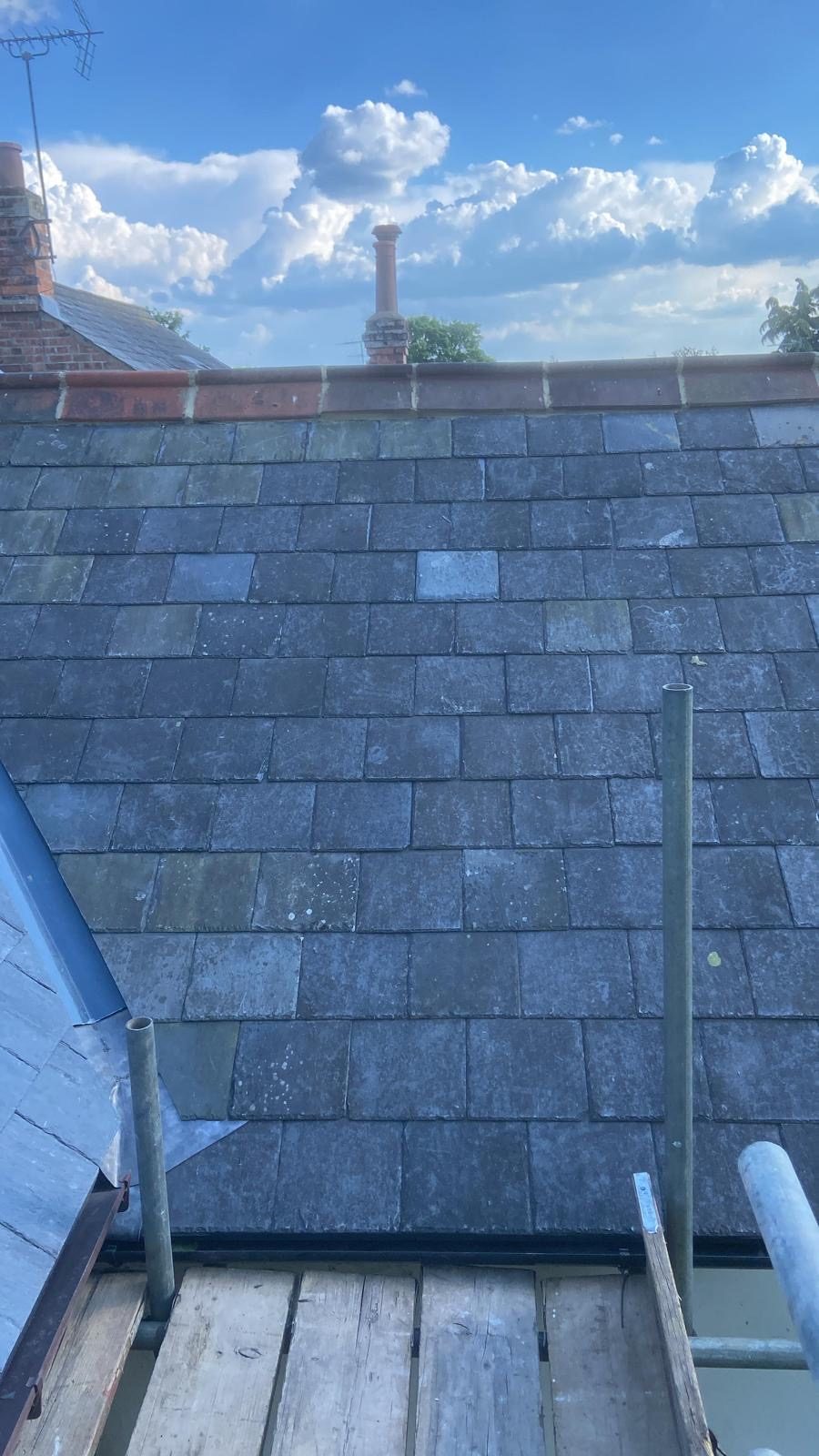 Slate slope up to a red clay ridge with lead at the eaves