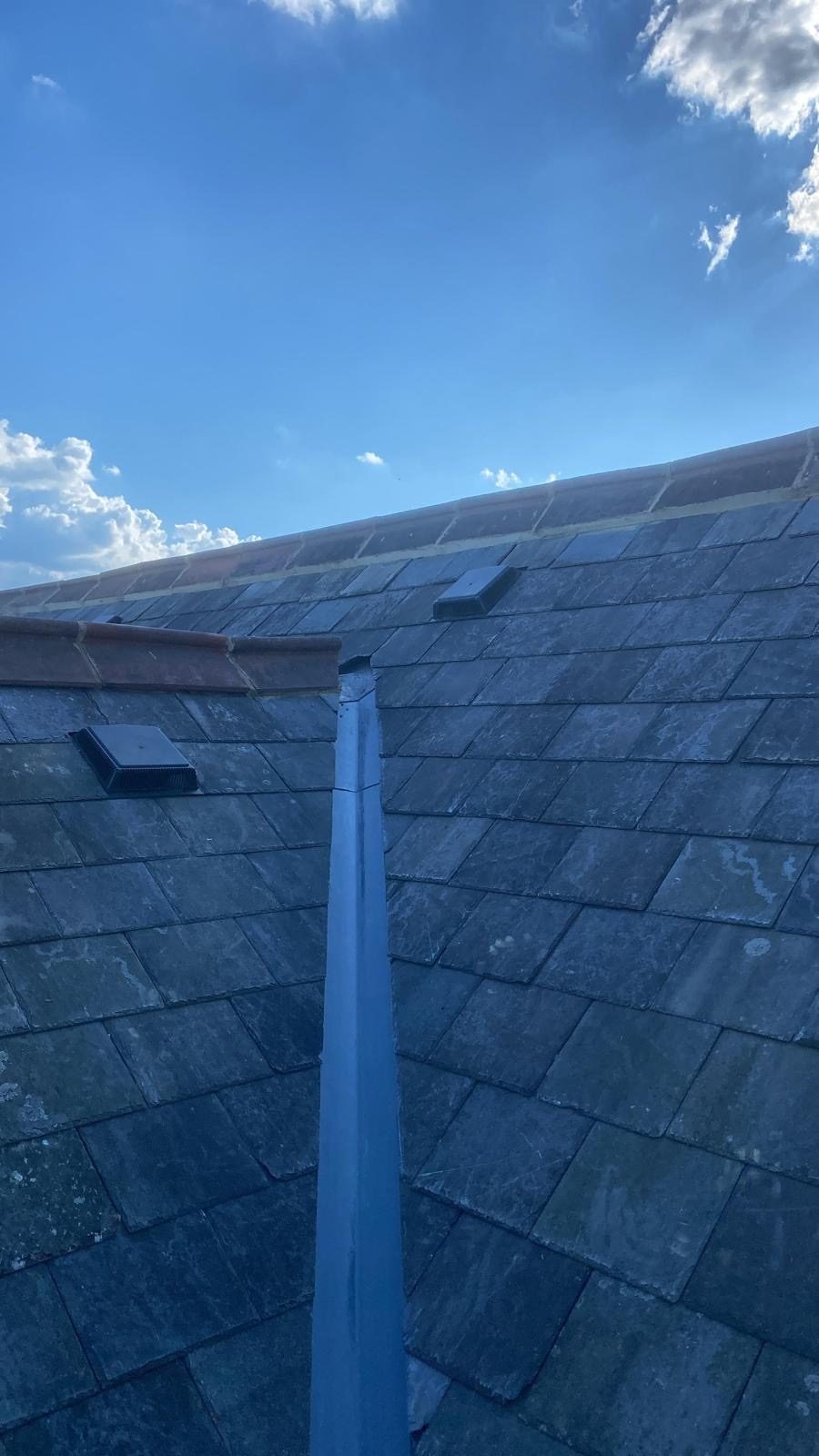 Slate slopes meeting at a lead hip roll with roof vents